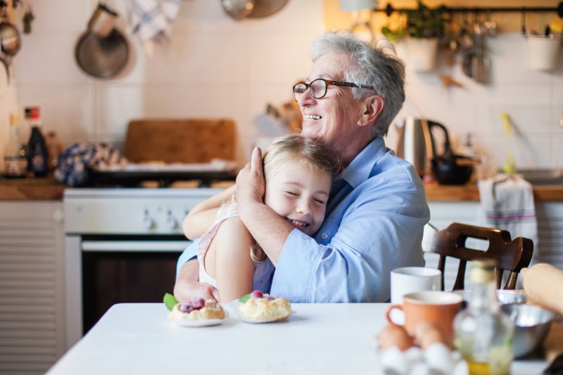 Why Do I Need a Humidifier in the Fall? Photo of a grandmother hugging her granddaughter in a kitchen.